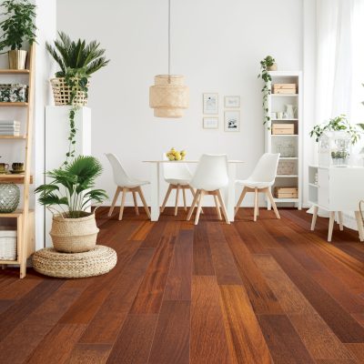 Pouf and brown rug near white cupboard in natural dining room interior with white chairs, plants and wooden shelves